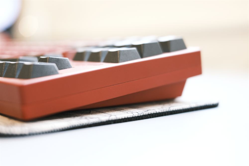 Side-profile macro of charcoal keys with warm bokeh